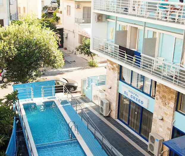 Sininen vesi-uima-allas aidalla ympäröitynä, sijaitsee hotellin vieressä, jossa sininen julkisivu. (Tekoälyn luoma teksti)