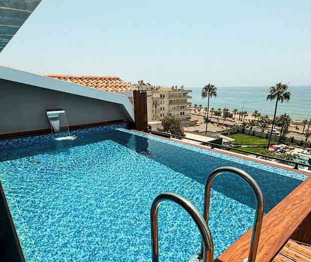 Pieni uima-allas katolla näkymänä merelle ja kaupunkimaisemaan. (Tekoälyn luoma teksti)