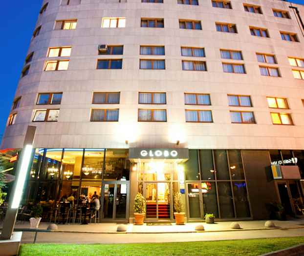 Hotelli, jossa on valaistu julkisivu ja sisäänkäynti, kuvattu hämärässä. (Tekoälyn luoma teksti)