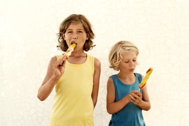 Kaksi lasta syö jätskipuikkoja