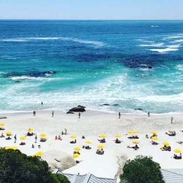 Clifton Beach, vaalea hiekkaranta aurinkovarjoisnen ja sinisen erisävyissä aaltoileva merisöder om Kapstaden.