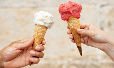 Kaksi kättä joista toisessa valkoinen ja toisessa punainen jäätelötötterö