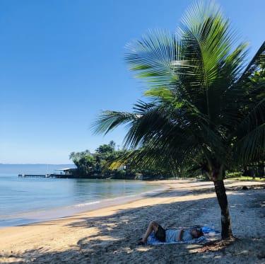 Jessica lepää palmujen varjossa rannalla