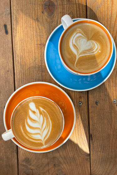 Kaksi kahvikuppia, joissa on koristettu maitovaahto