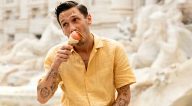 Mies istuu suihkulähteellä Roomassa syöden jäätelöä