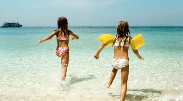 Kaksi pientä tyttöä rannalla Thaimaassa