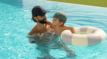 Isä ja poika uimassa uima-altaassa
