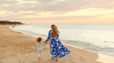 Nainen ja lapsi rannalla kävelemässä