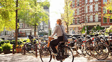 Nainen pyuöräilee Amsterdamissa
