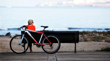 Pyöräilijä pitää taukoa ja istuu penkillä merinäköalaa ihaillen