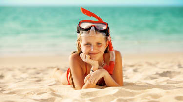 Tyttö snorklausvarusteissa rannalla