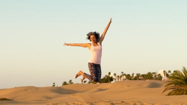 Nainen hyppää ilmaan hiekkadyyneillä