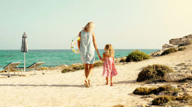 Äiti ja tytär kävelemässä hiekkarannalla