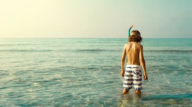 Poika seisoo vedessä snorkkeli kasvoillaan