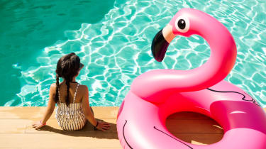 Tyttö istuu altaan reunalla vieressään iso flamingo-uimalelu
