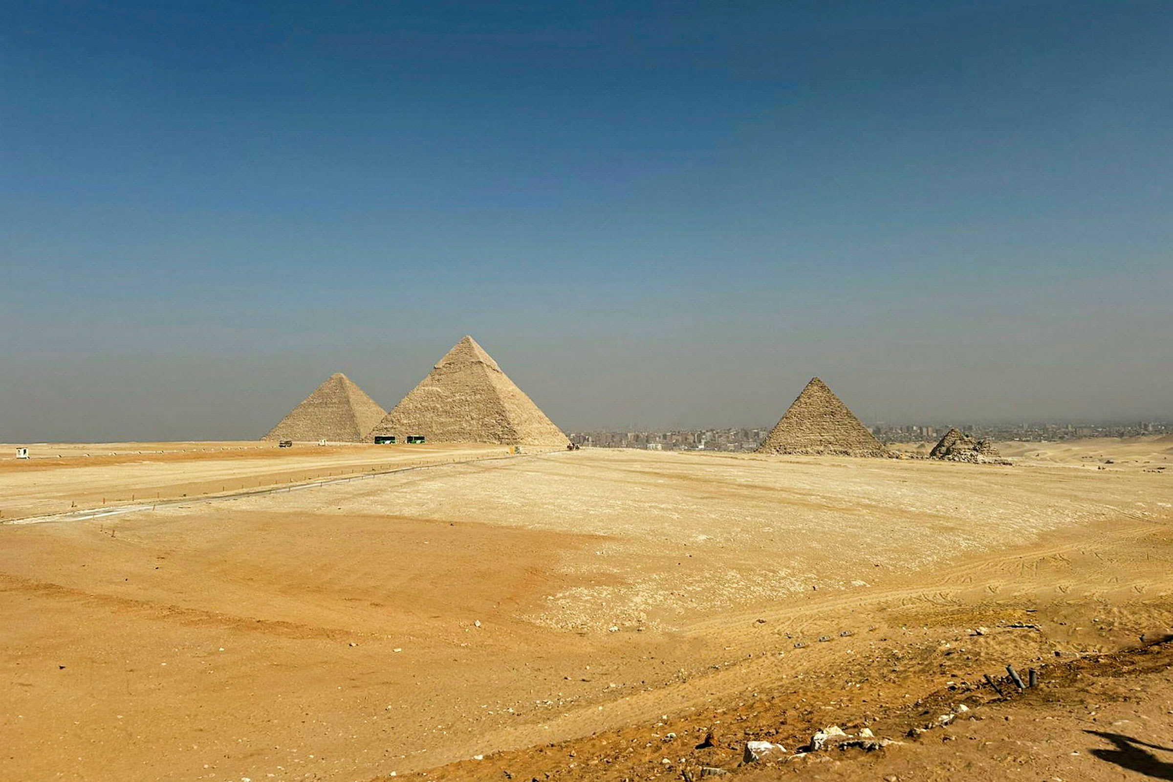 Kuvassa näkyvät Gizassa sijaitsevat suuret pyramidit ympäröityinä aavikkomaisemalla. (Tekoälyn luoma teksti)