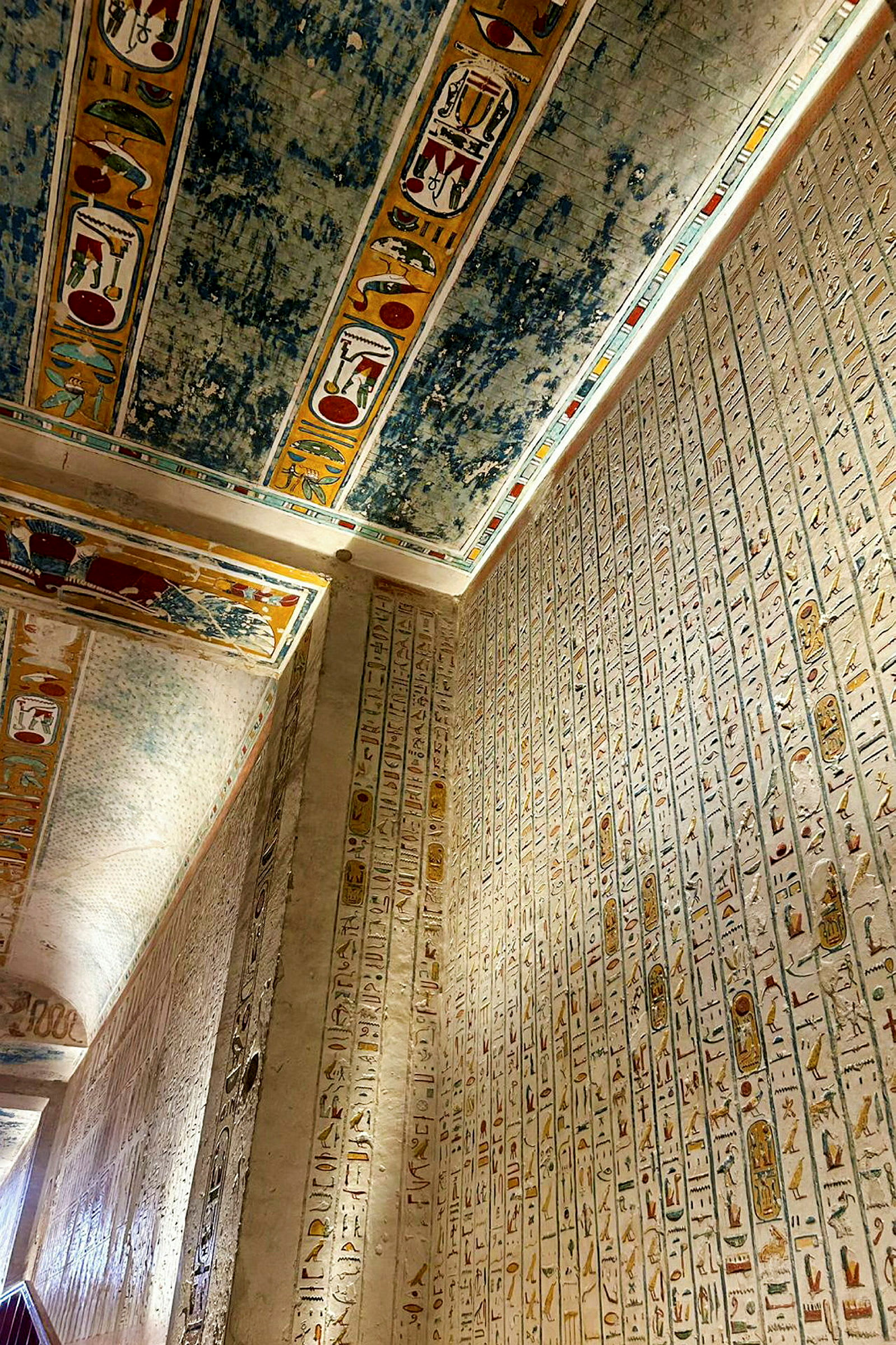 Seinä, joka on peitetty hieroglyfeillä ja katto värikkäillä koristeluilla vanhassa egyptiläisessä rakennelmassa. (Tekoälyn luoma teksti)