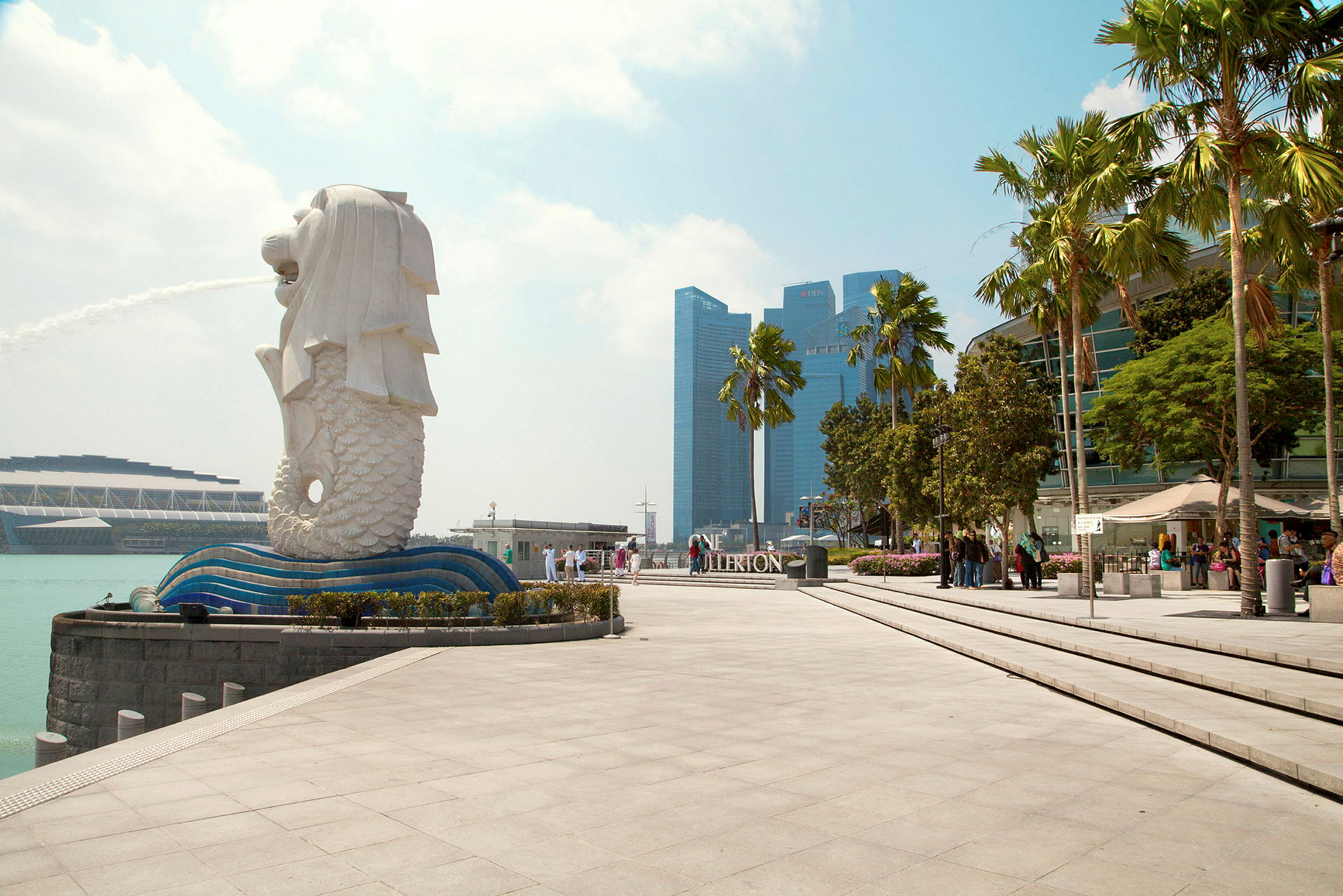 Kuva Merlion-patsasta Singaporessa suihkulähteen kanssa, ympärillä modernia arkkitehtuuria ja palmuja. (Tekoälyn luoma teksti)