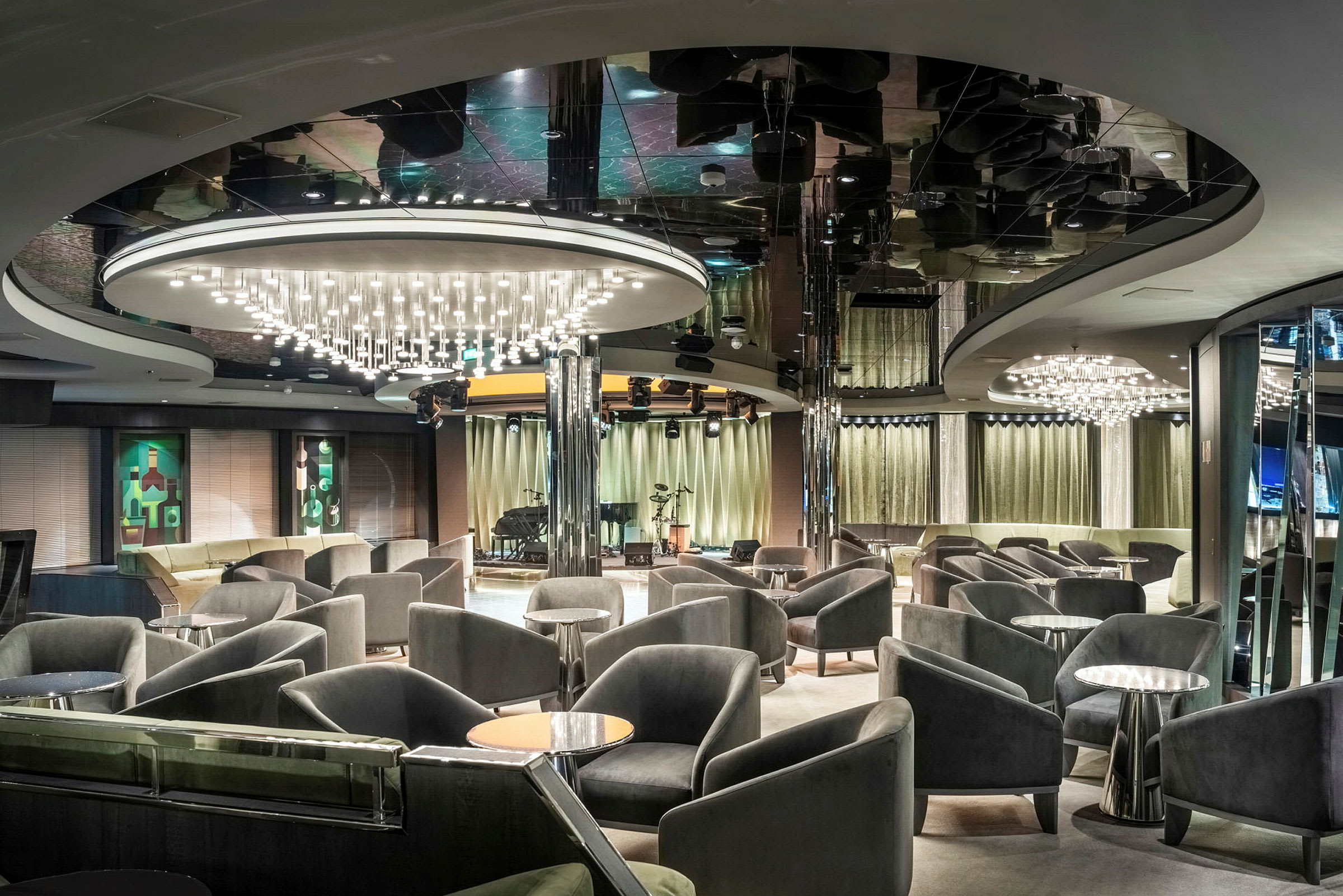 Lounge, jossa mukavat tuolit, pienet pöydät ja riippuvat kattokruunut. (Tekoälyn luoma teksti)