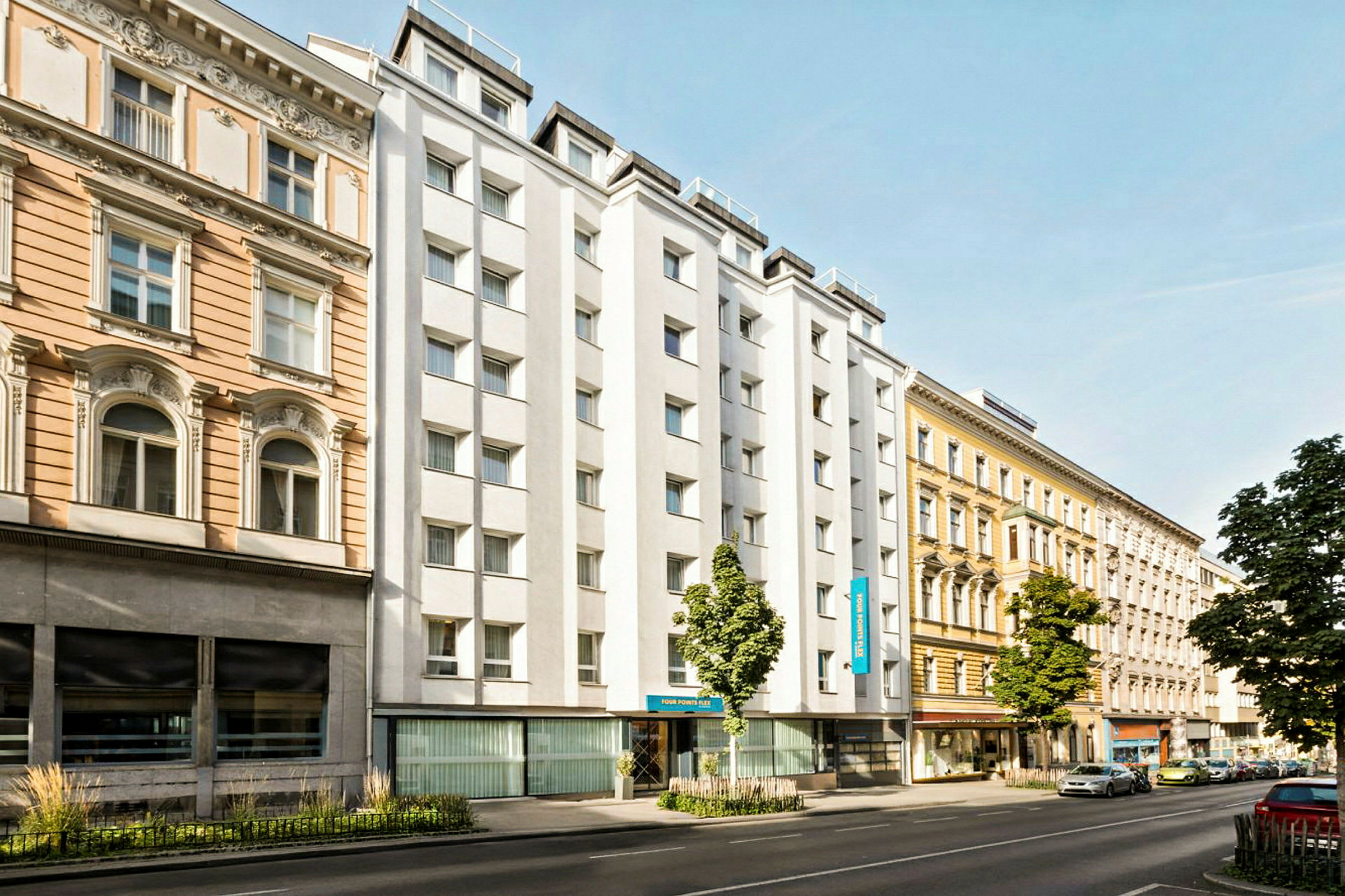 Kaupunkikatu, jossa on eri vuosikymmenten rakennuksia, mukaan lukien valkoseinäinen hotelli. (Tekoälyn luoma teksti)