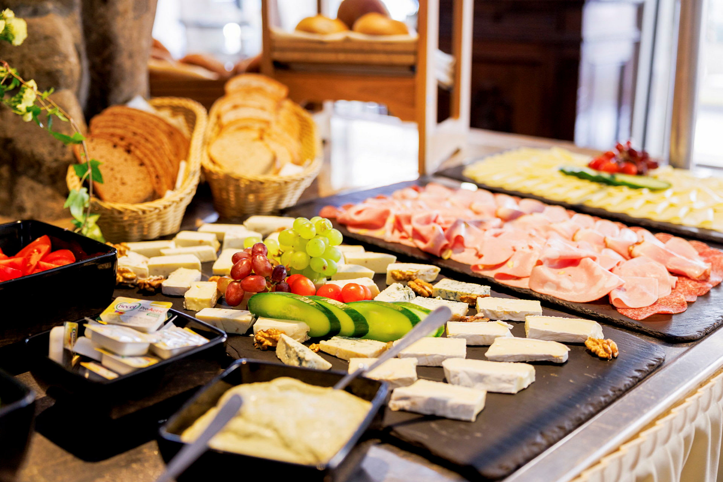 Buffet, jossa on erilaisia ruokia kuten juustoja, vihanneksia, lihaa ja leipää. (Tekoälyn luoma teksti)