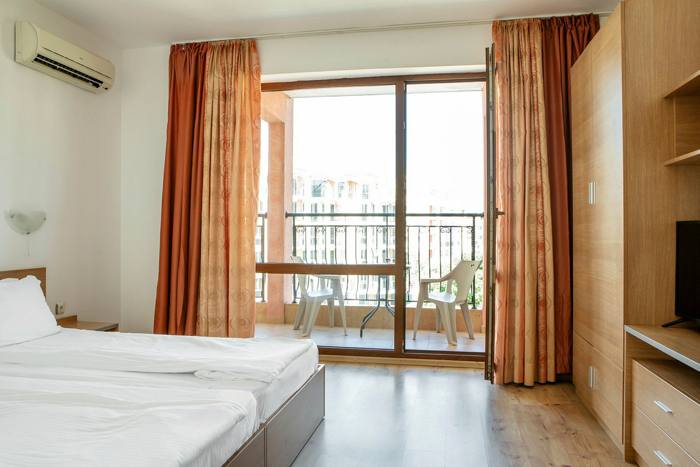 Hotellihuone, jossa sänky ja parveke tuoleineen. (Tekoälyn luoma teksti)