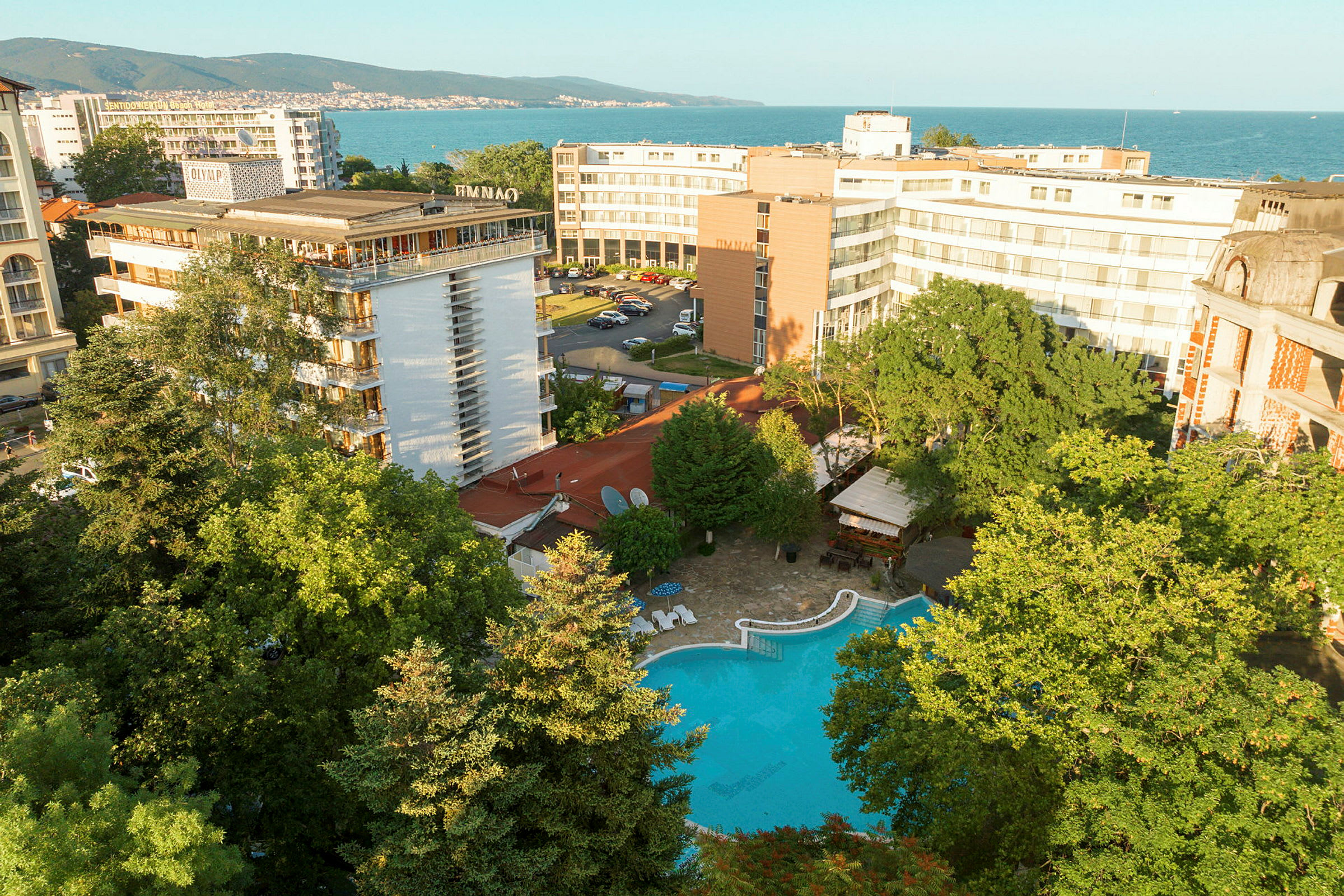 Hotellirakennuksia, uima-allas vehreyden ympäröimänä lähellä merta. (Tekoälyn luoma teksti)