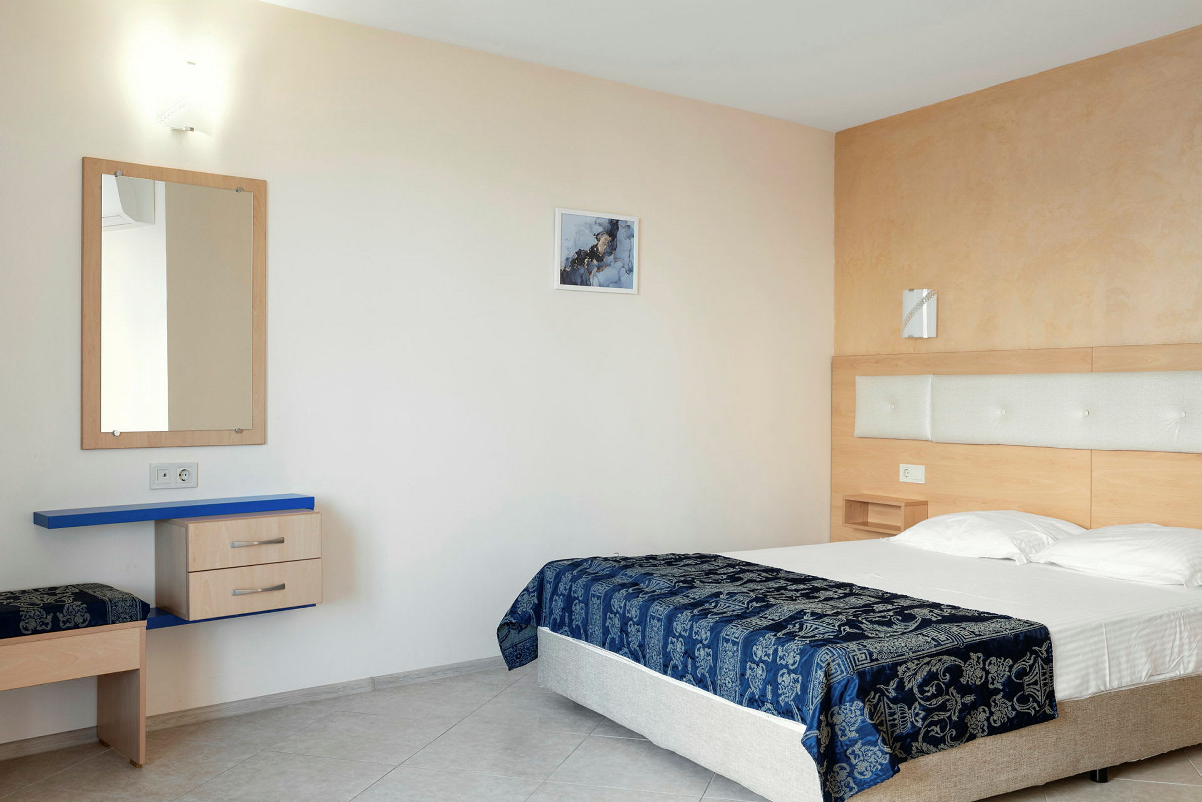 Hotellisänky sinisellä kuvioidulla peitteellä nykyaikaisessa huoneessa. (Tekoälyn luoma teksti)