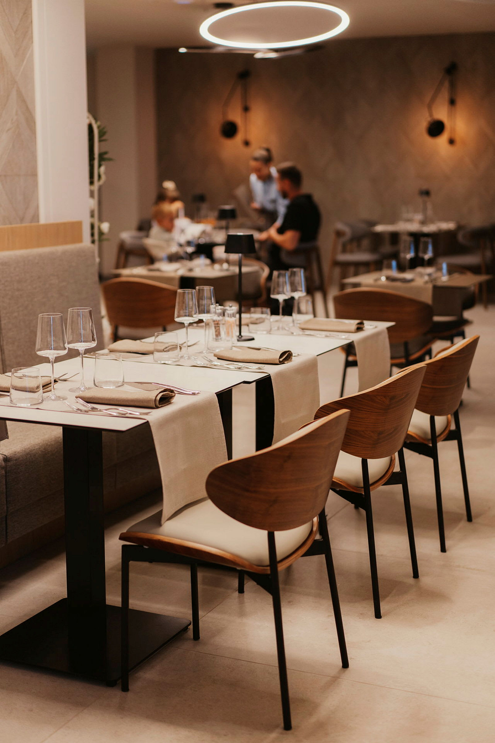 Modernisti sisustettu ravintola-alue, jossa on katettuja pöytiä ja tyylikkäitä tuoleja. (Tekoälyn luoma teksti)