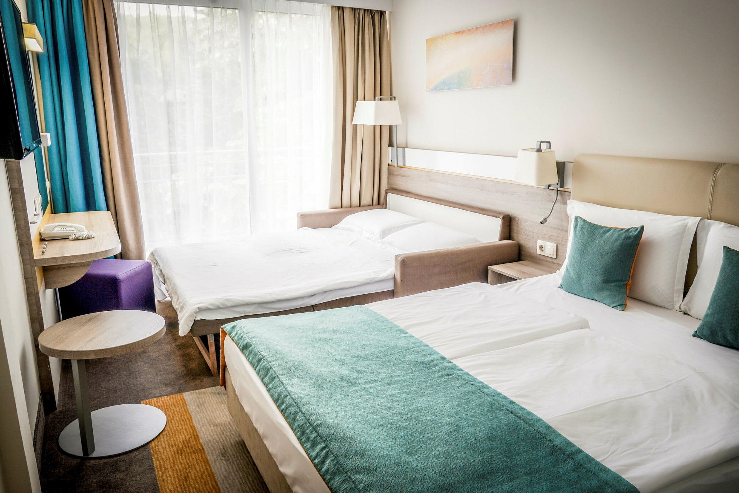 Kaksi sänkyä hotellihuoneessa, jossa suuri ikkunaseinä ja verhot. (Tekoälyn luoma teksti)