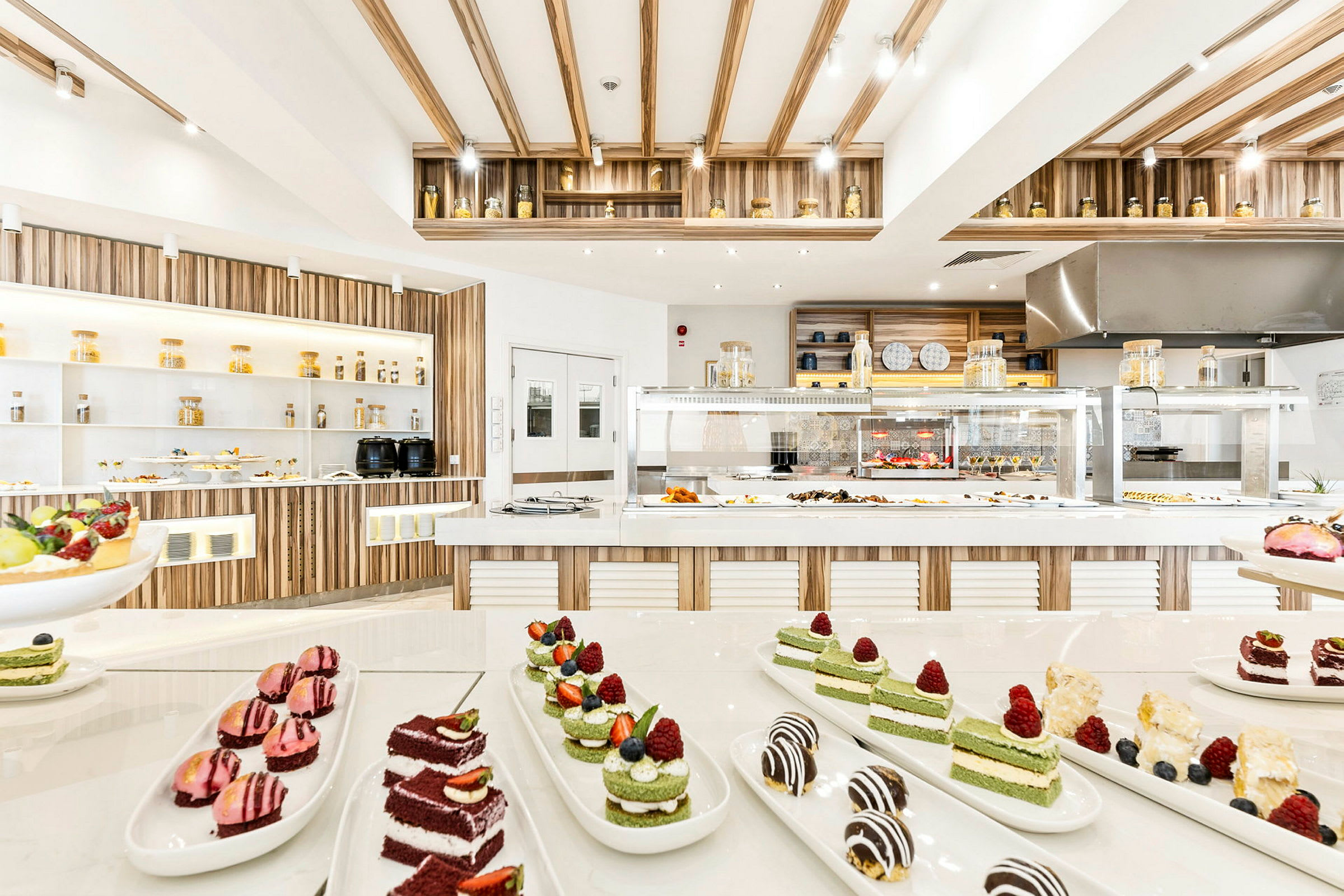 Moderni ja valoisa buffet-alue, jossa tarjolla erilaisia jälkiruokia ja asetelmia. (Tekoälyn luoma teksti)