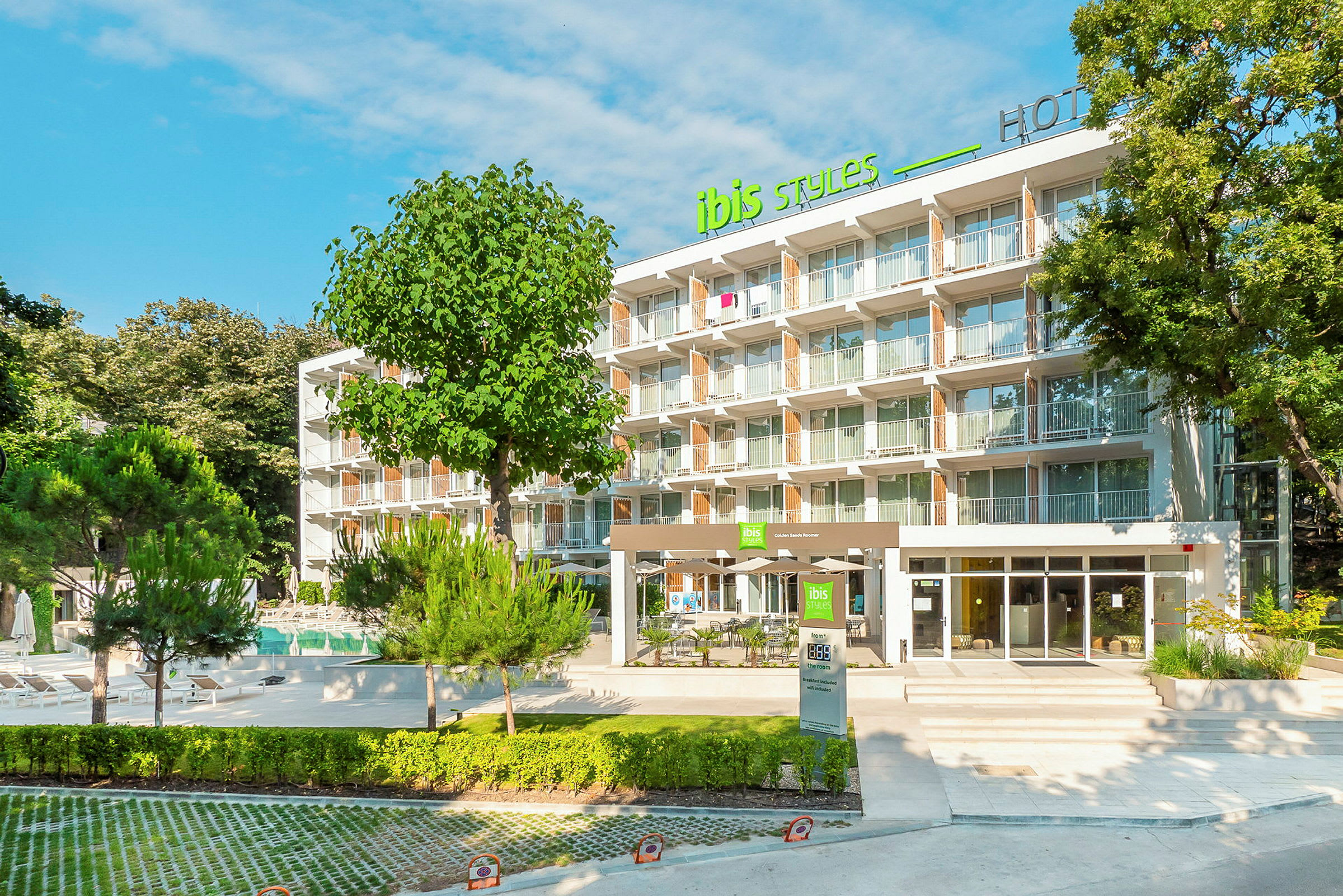 Moderni hotellirakennus, jossa on useita kerroksia, ympäröitynä vehreydellä ja puilla. (Tekoälyn luoma teksti)