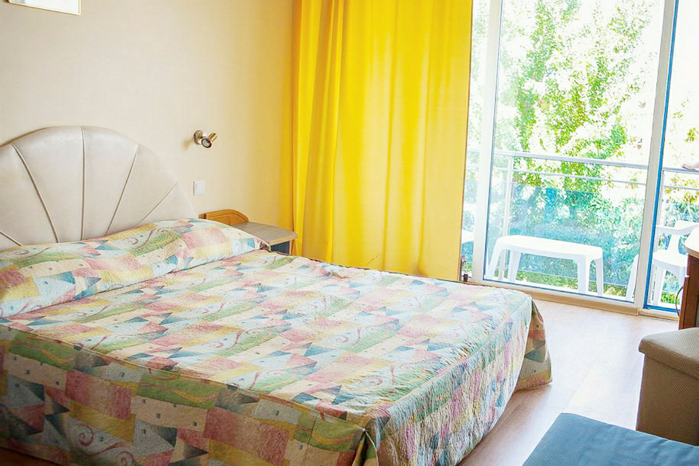 Hotellihuone, jossa on sänky, keltaiset verhot ja ikkuna näkymällä. (Tekoälyn luoma teksti)