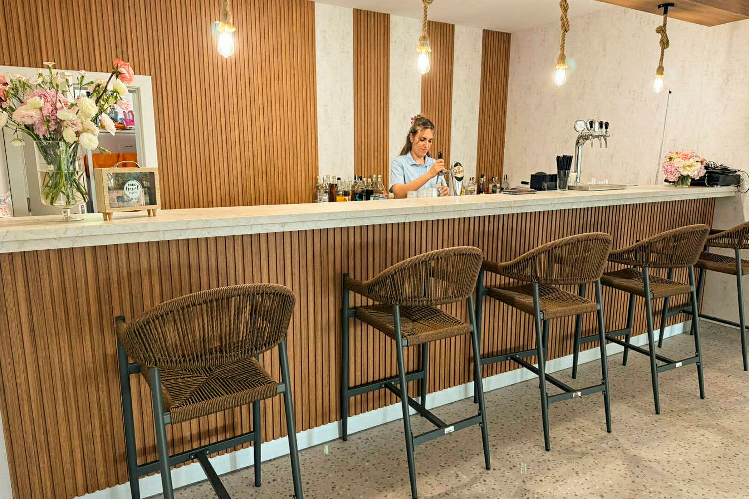 Baaritiski, jossa on korkeat tuolit ja puuyksityiskohtia sisustuksessa. (Tekoälyn luoma teksti)