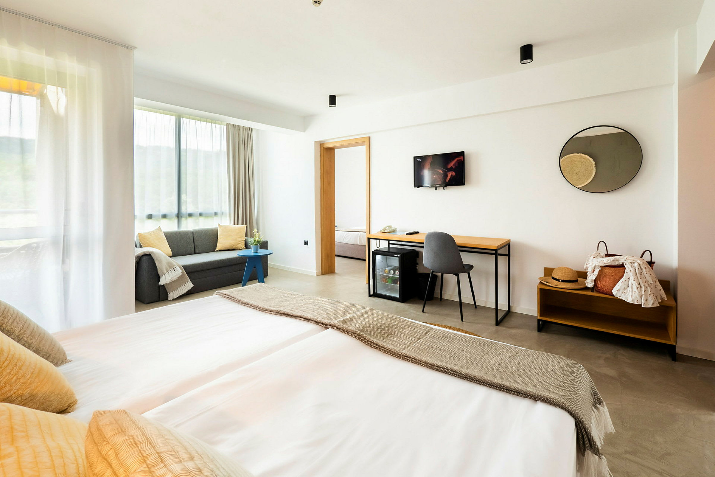 Moderni hotellihuone, jossa on parivuode, sohva ja työpöytä. (Tekoälyn luoma teksti)