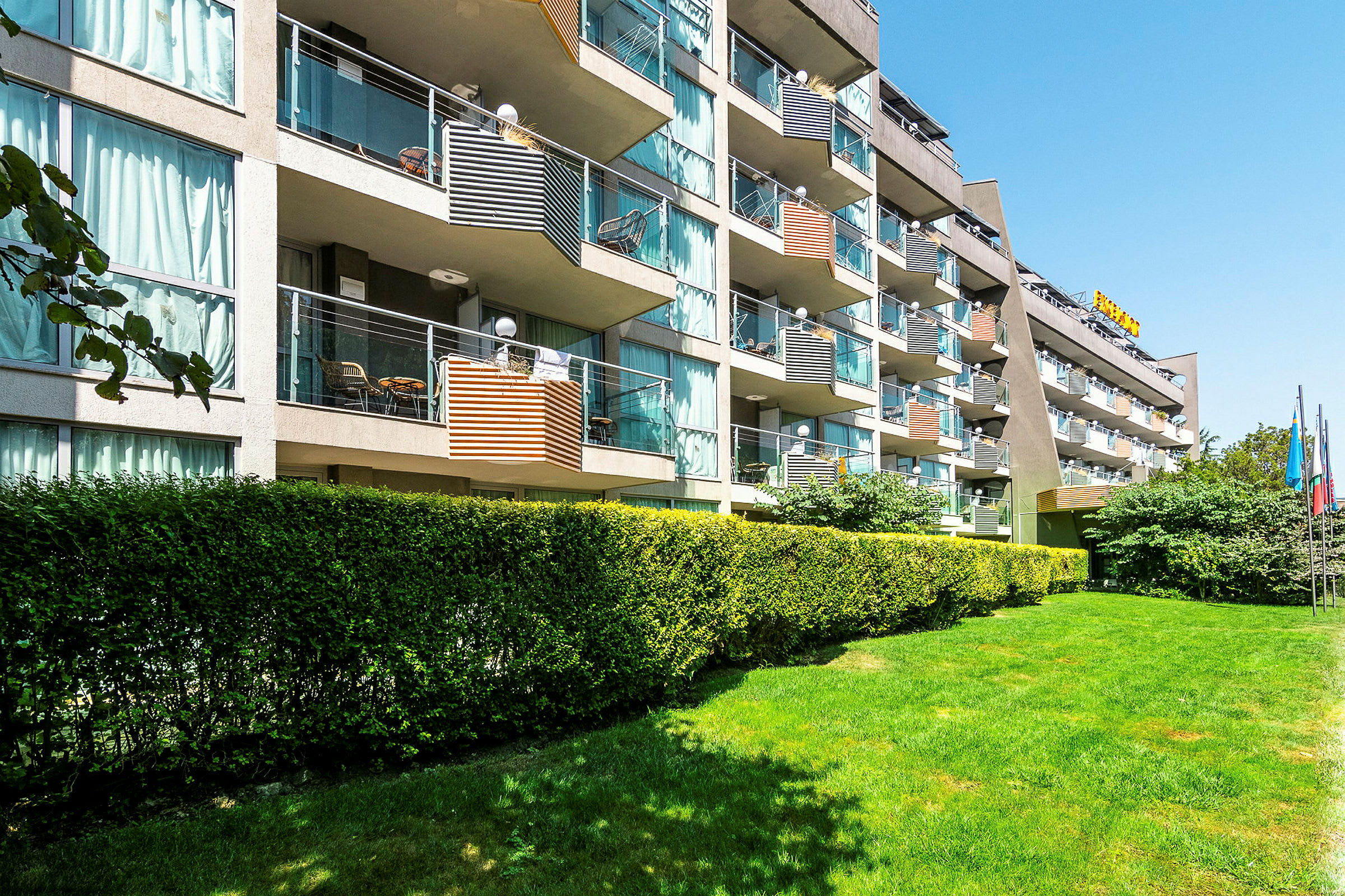 Kuva hotellirakennuksesta, jossa on useita parvekkeita ja ympäröivää vihreyttä. (Tekoälyn luoma teksti)