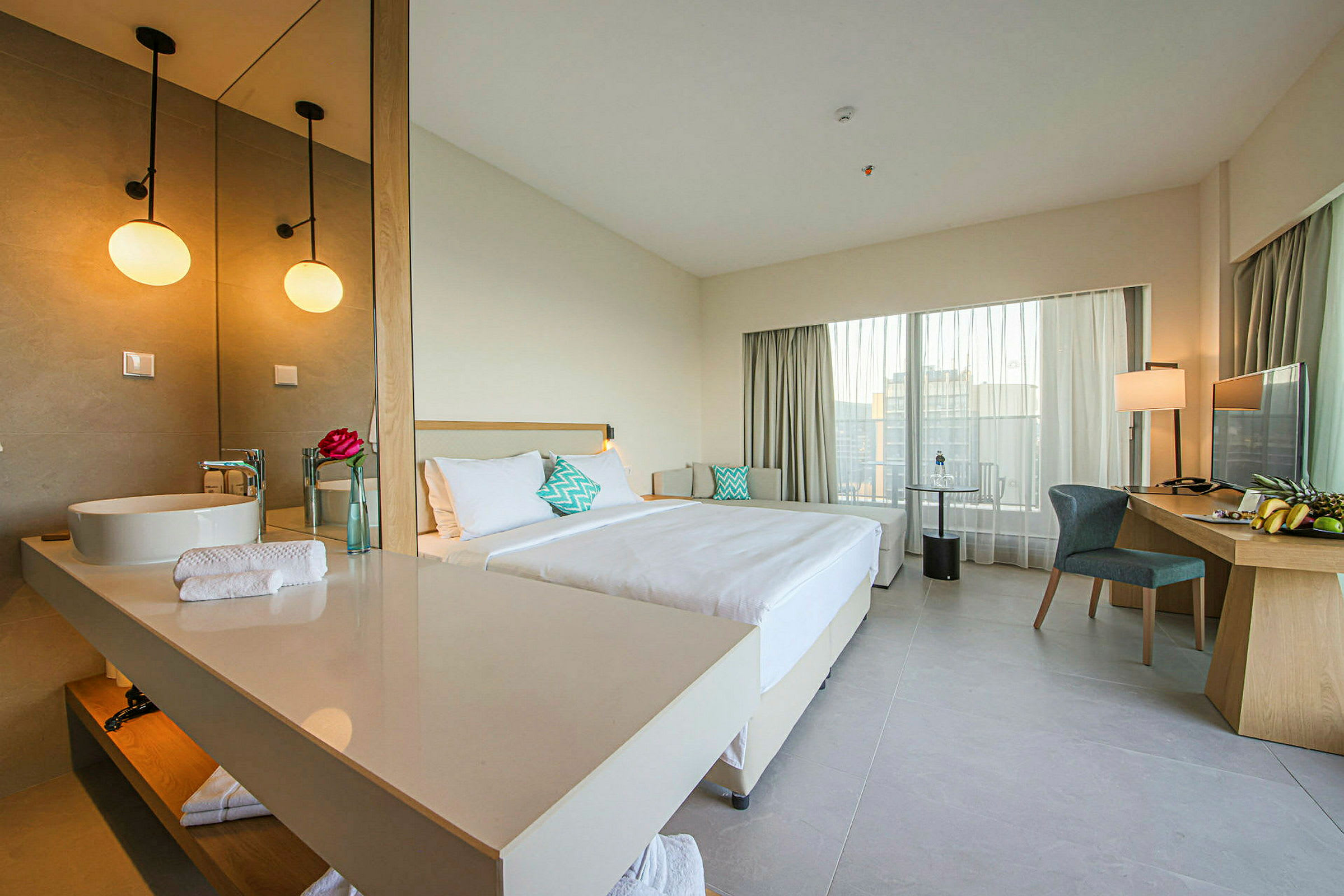 Hotellihuone, jossa on parivuode, työpöytä tuoleineen ja iso peili pesualtaan luona. (Tekoälyn luoma teksti)