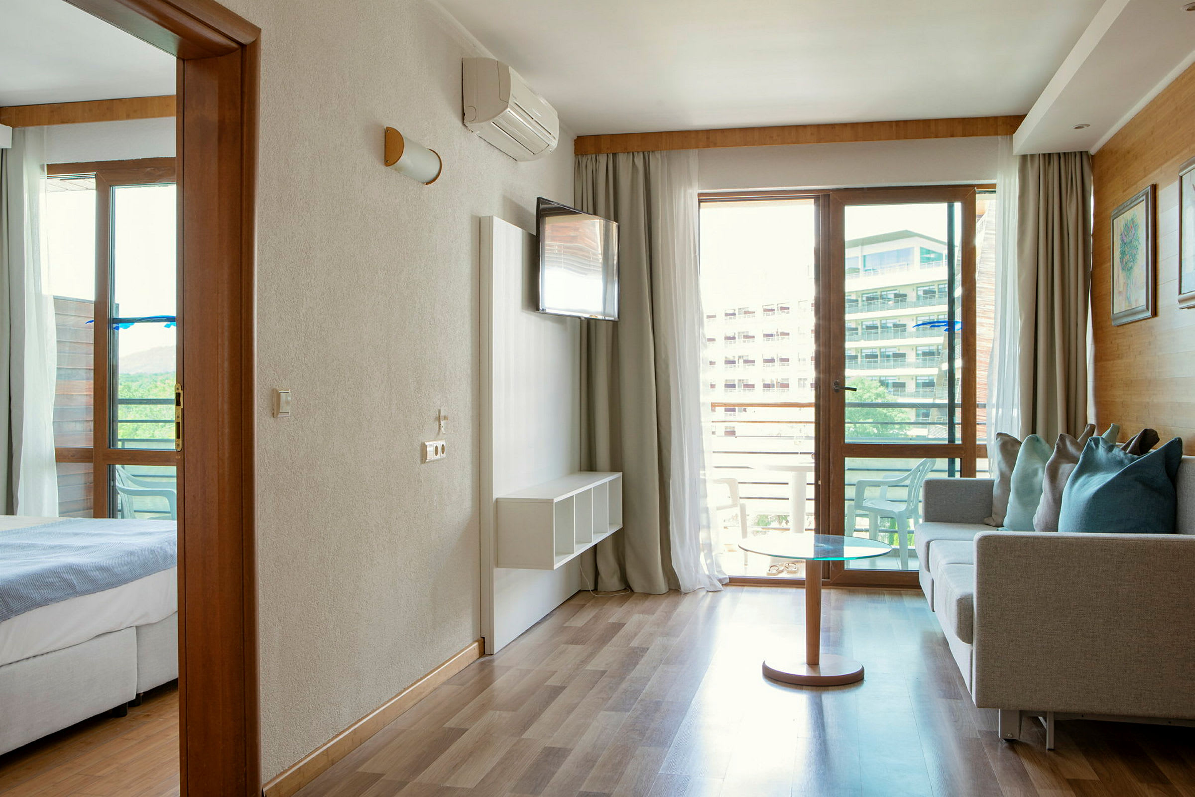 Hotellihuone, jossa olohuone ja makuuhuone sekä parvekkeelle johtava ovi. (Tekoälyn luoma teksti)