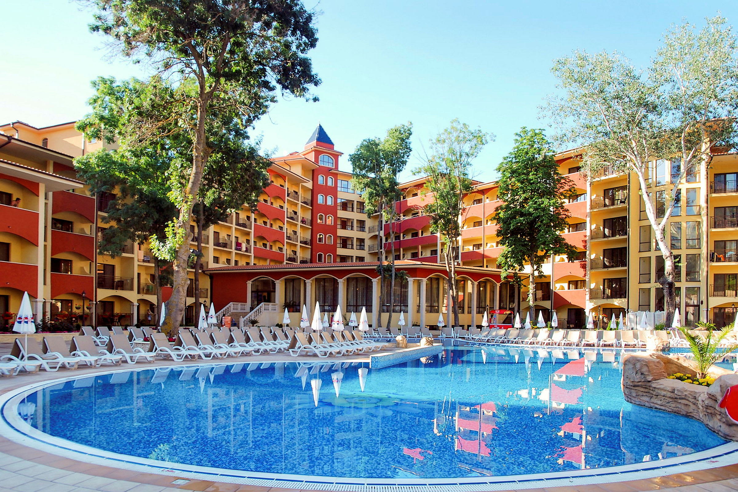 Kuva hotellista, jossa on suuri uima-allas ja aurinkotuoleja ulkona. (Tekoälyn luoma teksti)