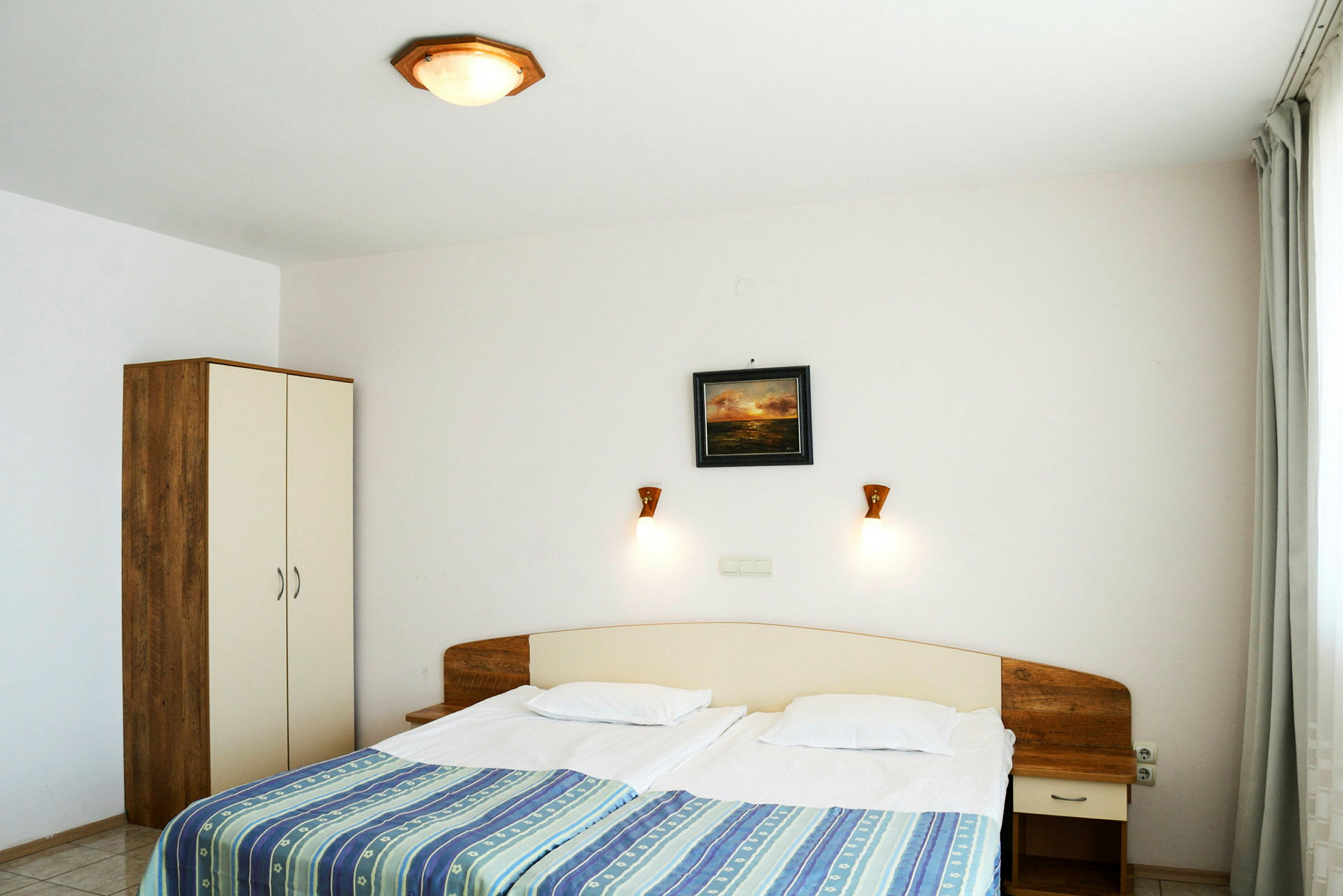 Hotellihuone, jossa on parivuode, yöpöytä ja vaatekaappi. (Tekoälyn luoma teksti)