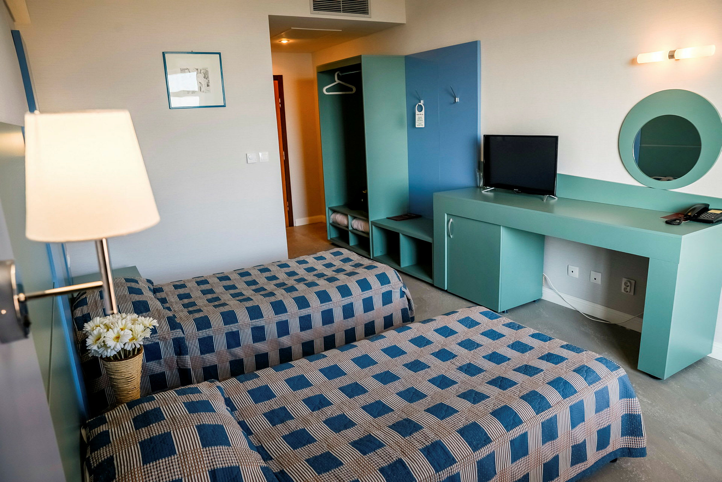 Hotellihuone, jossa kaksi yhden hengen vuodetta, tv ja vaatekaappi. (Tekoälyn luoma teksti)