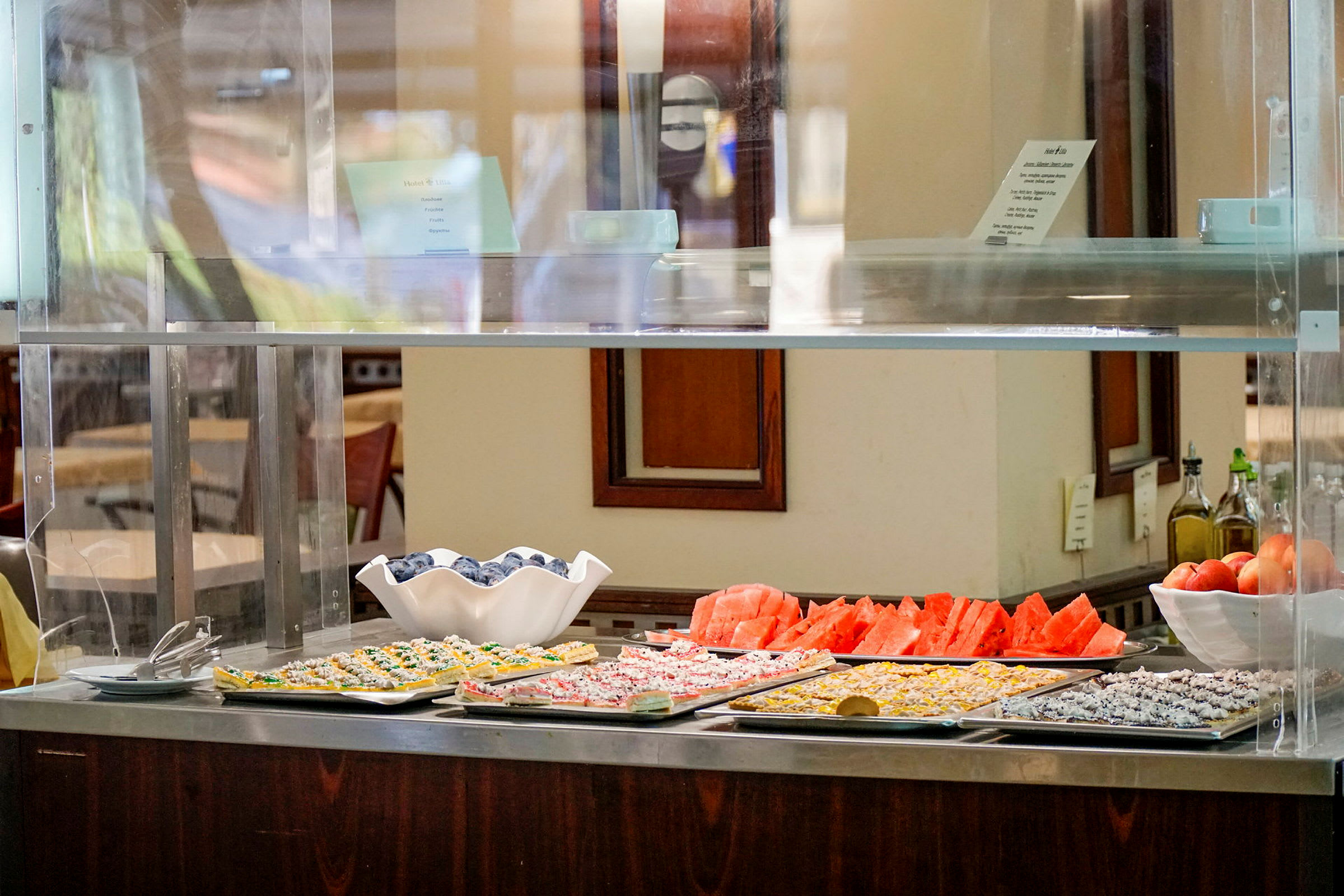 Kuva buffet-tiskistä, jossa on tarjoiltuja ruokia ja leikattuja vesimeloneja. (Tekoälyn luoma teksti)