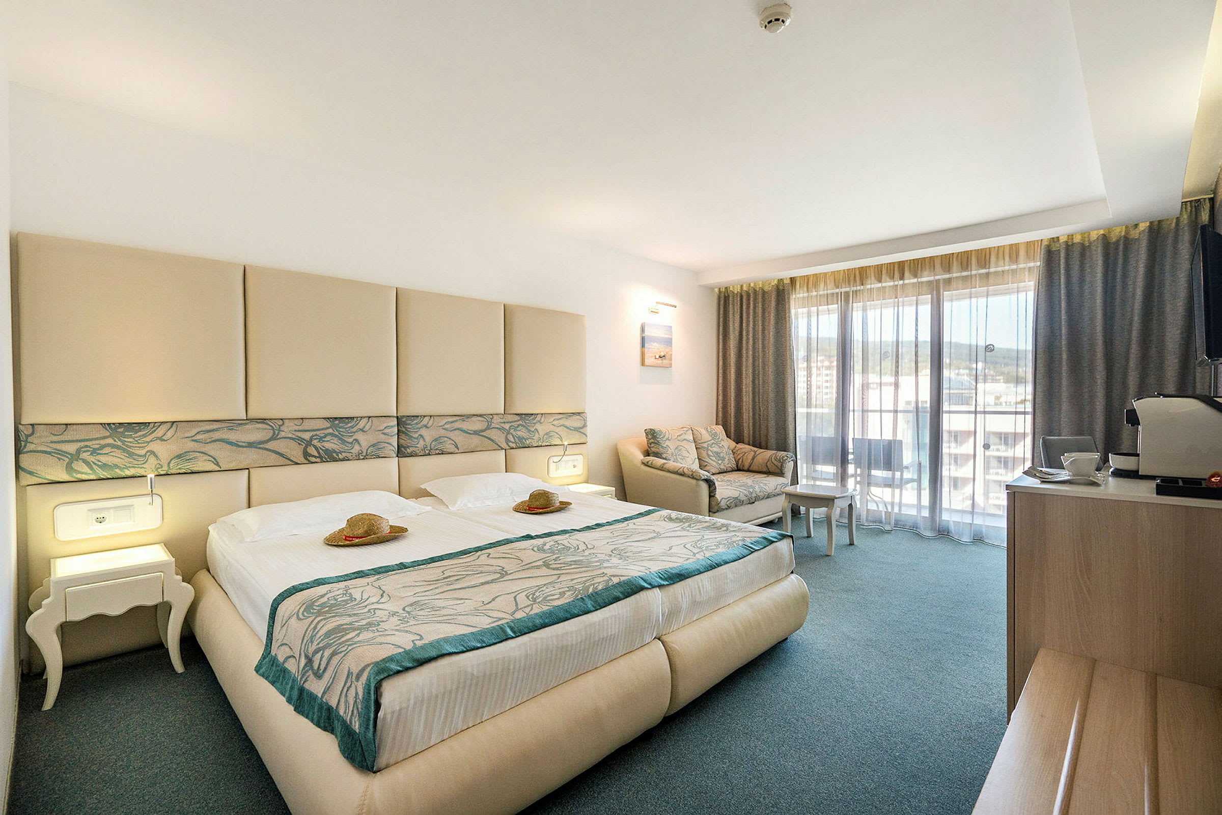 Hotellihuone, jossa parivuode, sohva ja parveke. (Tekoälyn luoma teksti)