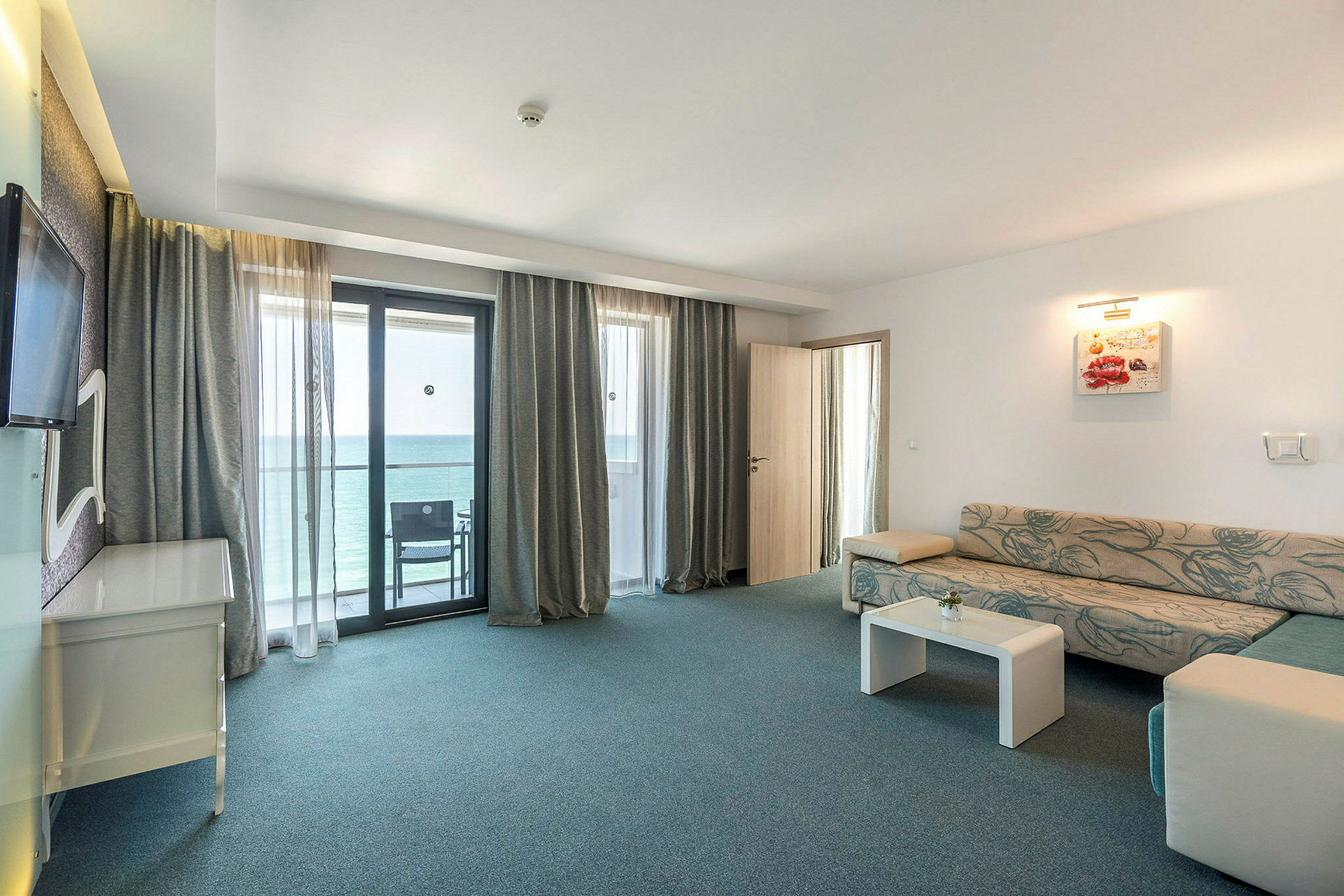 Hotellihuone, jossa on istuinalue ja parvekenäkymä. (Tekoälyn luoma teksti)