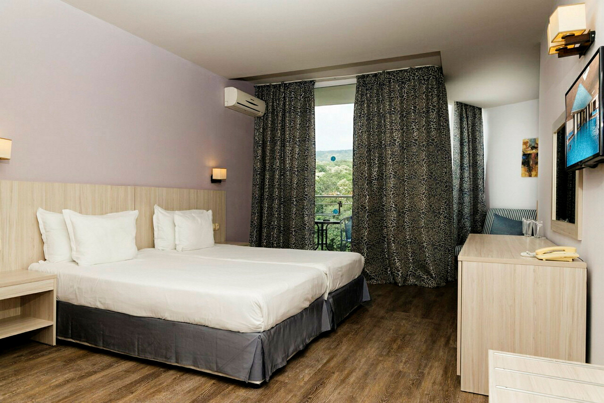 Hotellihuone, jossa kaksi erillistä vuodetta, työpöytä ja ikkuna maisemilla. (Tekoälyn luoma teksti)