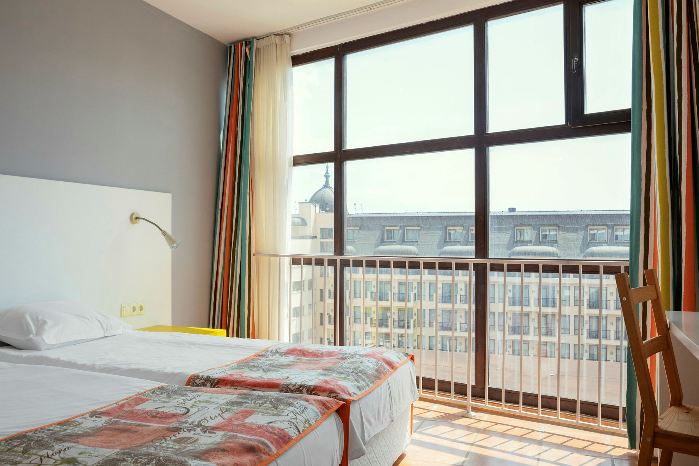 Hotellihuone, jossa kaksi erillistä sänkyä ja suuri ikkuna kaupunkinäkymään. (Tekoälyn luoma teksti)