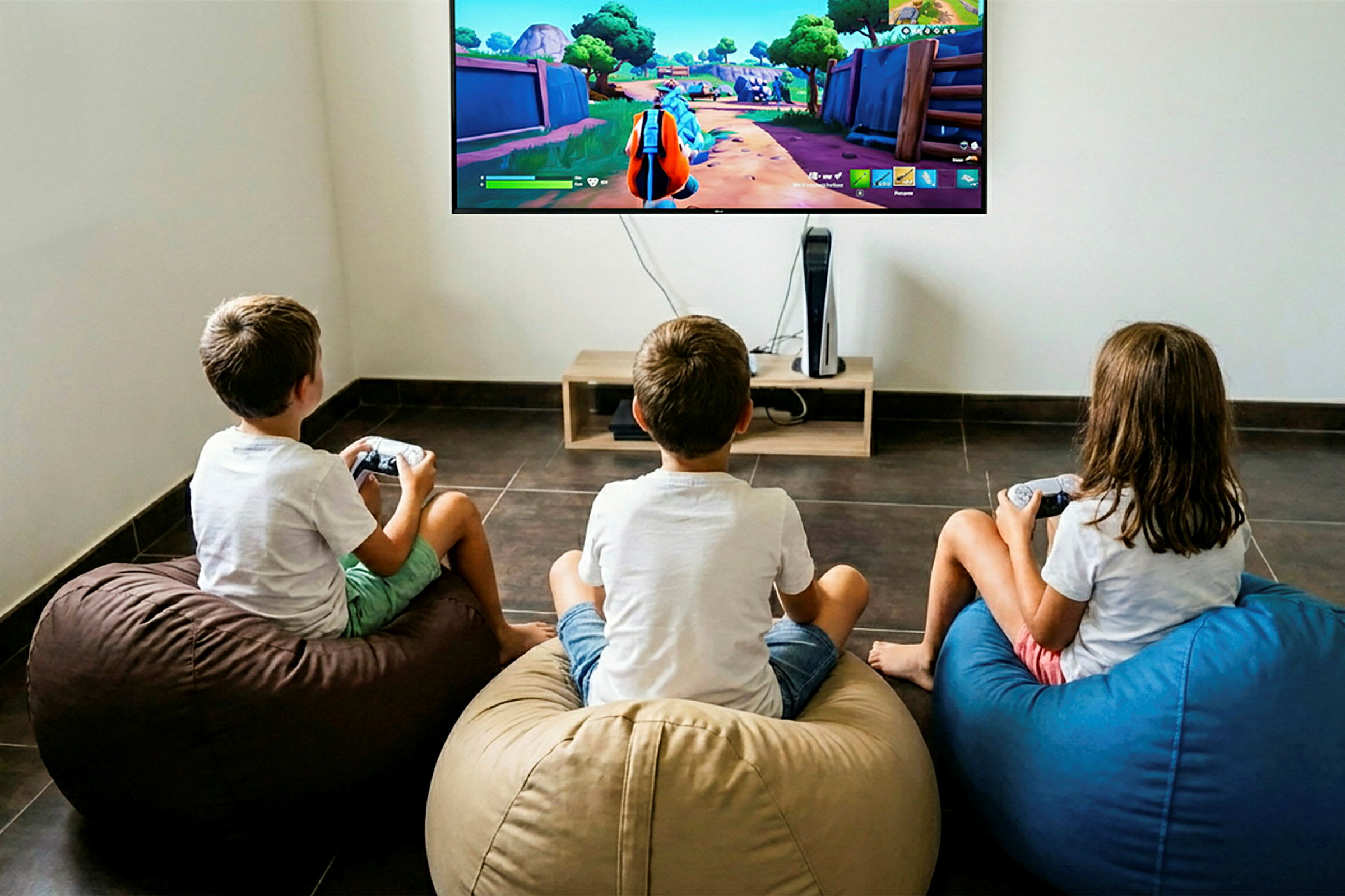 Kolme lasta istuu säkkituoleilla ja pelaa videopeliä isolla seinälle kiinnitetyllä televisiolla. (Tekoälyn luoma teksti)