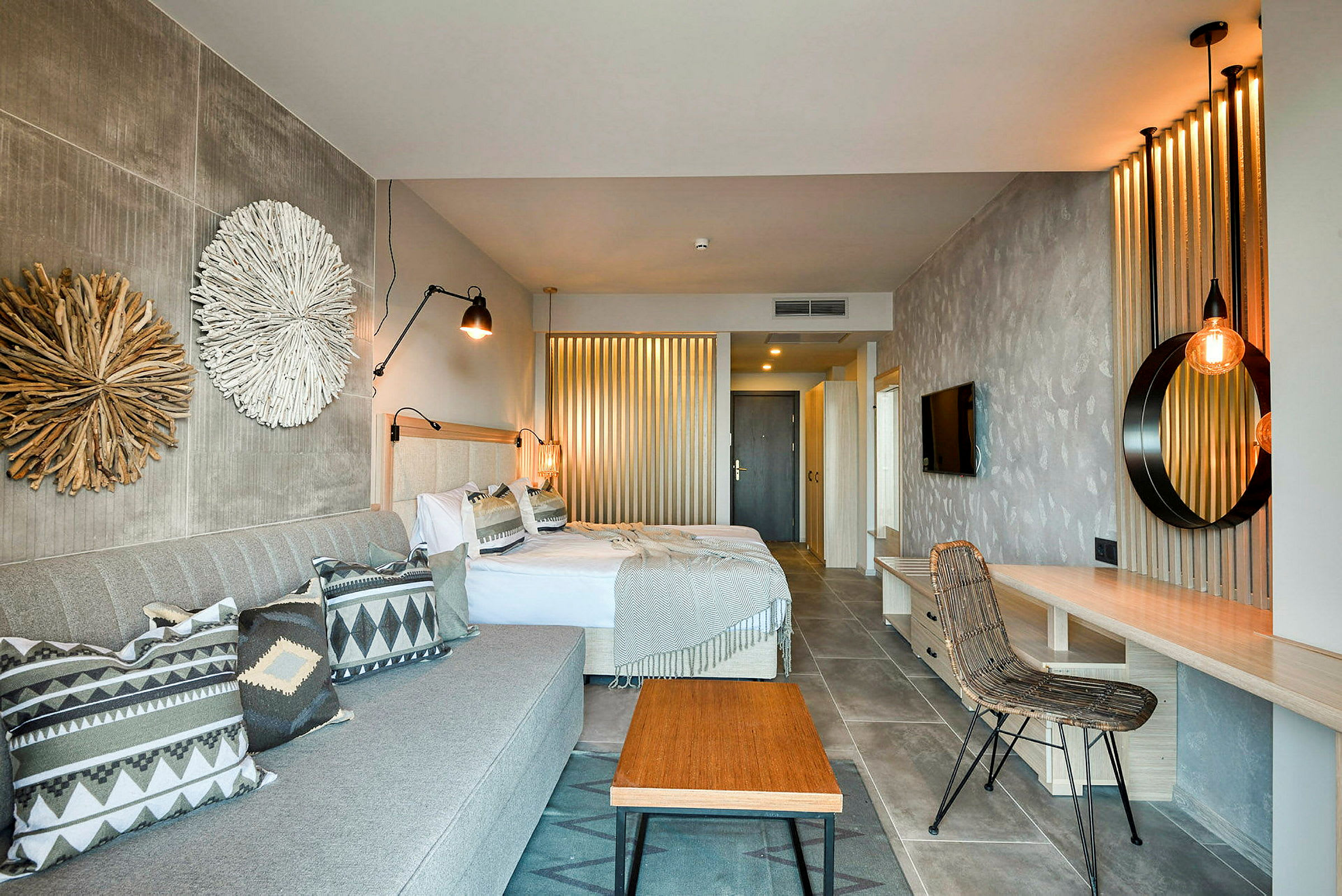 Hotellihuone, jossa kaksi sänkyä, sohva ja sisustuselementtejä. (Tekoälyn luoma teksti)