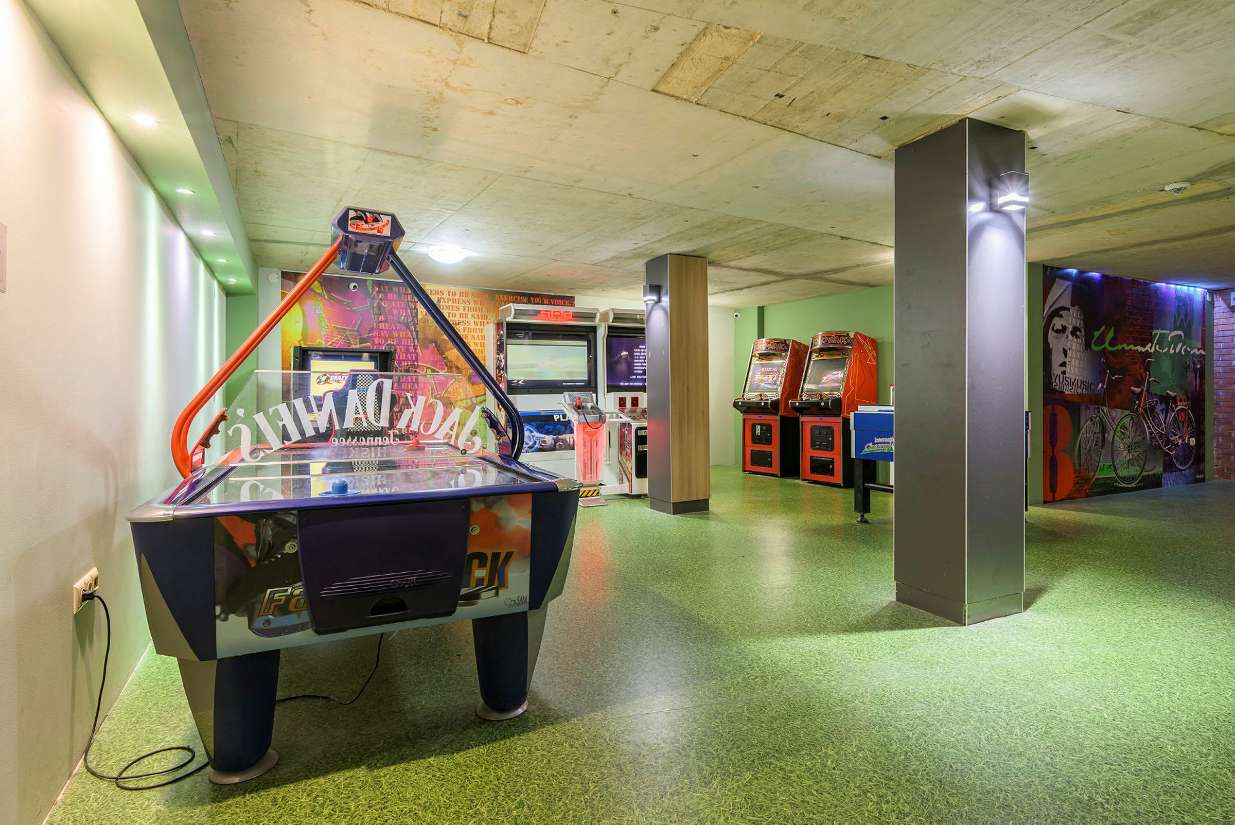Kuva pelihuoneesta, jossa on ilmakiekkopeli ja arcade-koneita. (Tekoälyn luoma teksti)