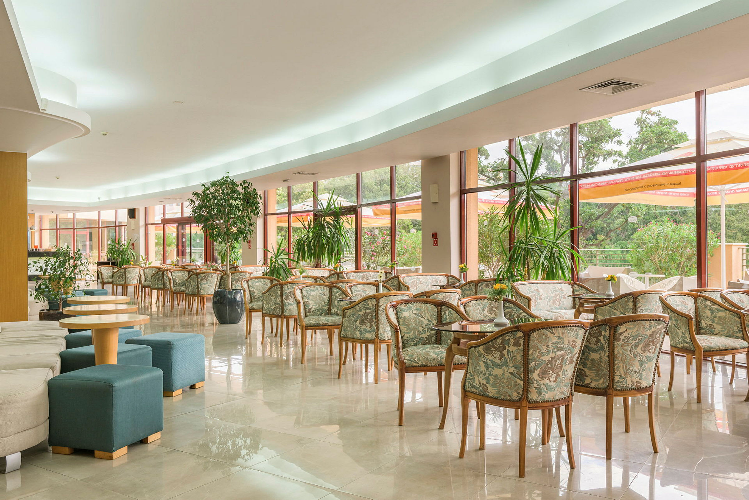 Tilava lounge, jossa on paljon tuoleja ja pöytiä suurten ikkunoiden edessä. (Tekoälyn luoma teksti)